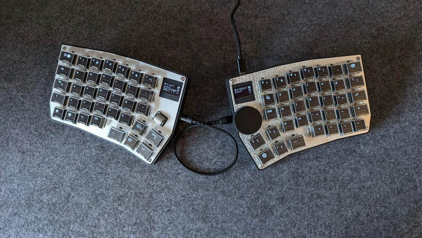 Both Split72 halves on a desk, connected by the link cable, keycap OLEDs showing their legends