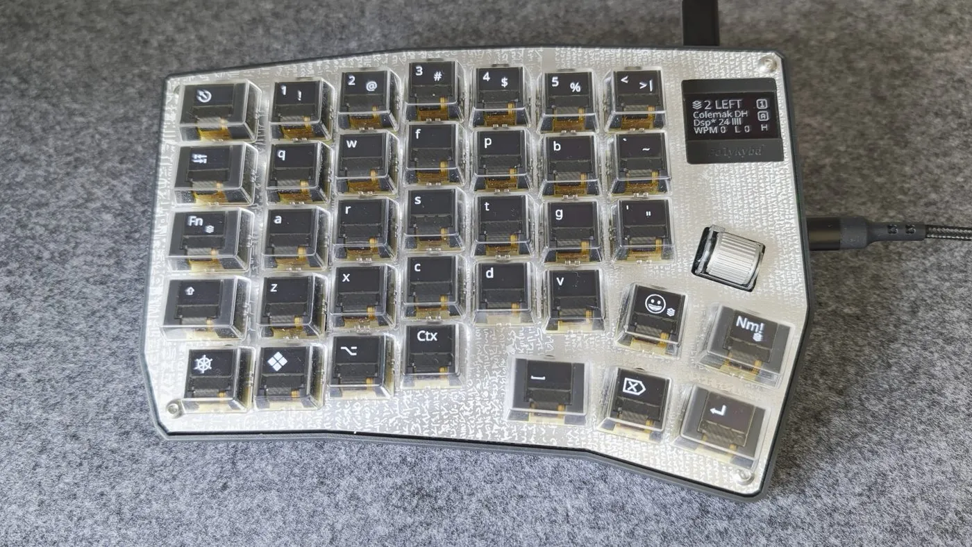 An assembled split72 left half, each keycap OLED showing its Colemak-DH legend, with the status display reading "2 LEFT / Colemak DH"